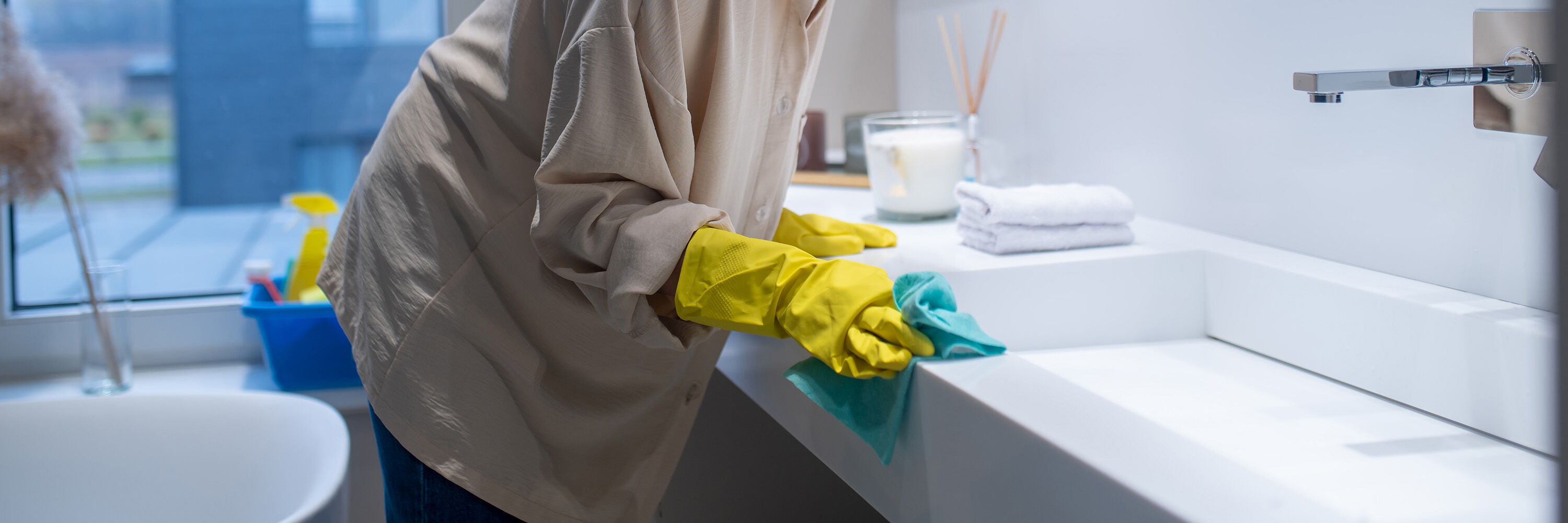 frau putzt waschtisch gr&uuml;ner lumpen und gelbe gummihandschuhe