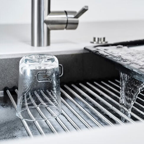 glas trocknet auf abtropfmatte auf waschbecken vor k&uuml;chenarmatur