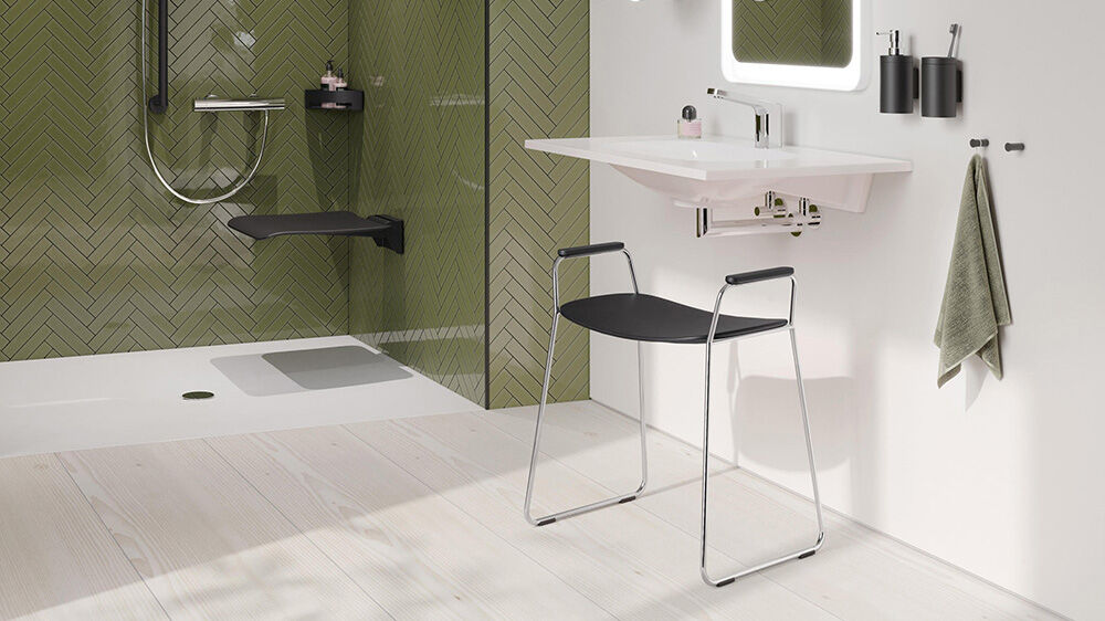 schwarzer bad hocker vor lavabo dahinter eine gr&uuml;n gekachelte dusche mit duschsitz